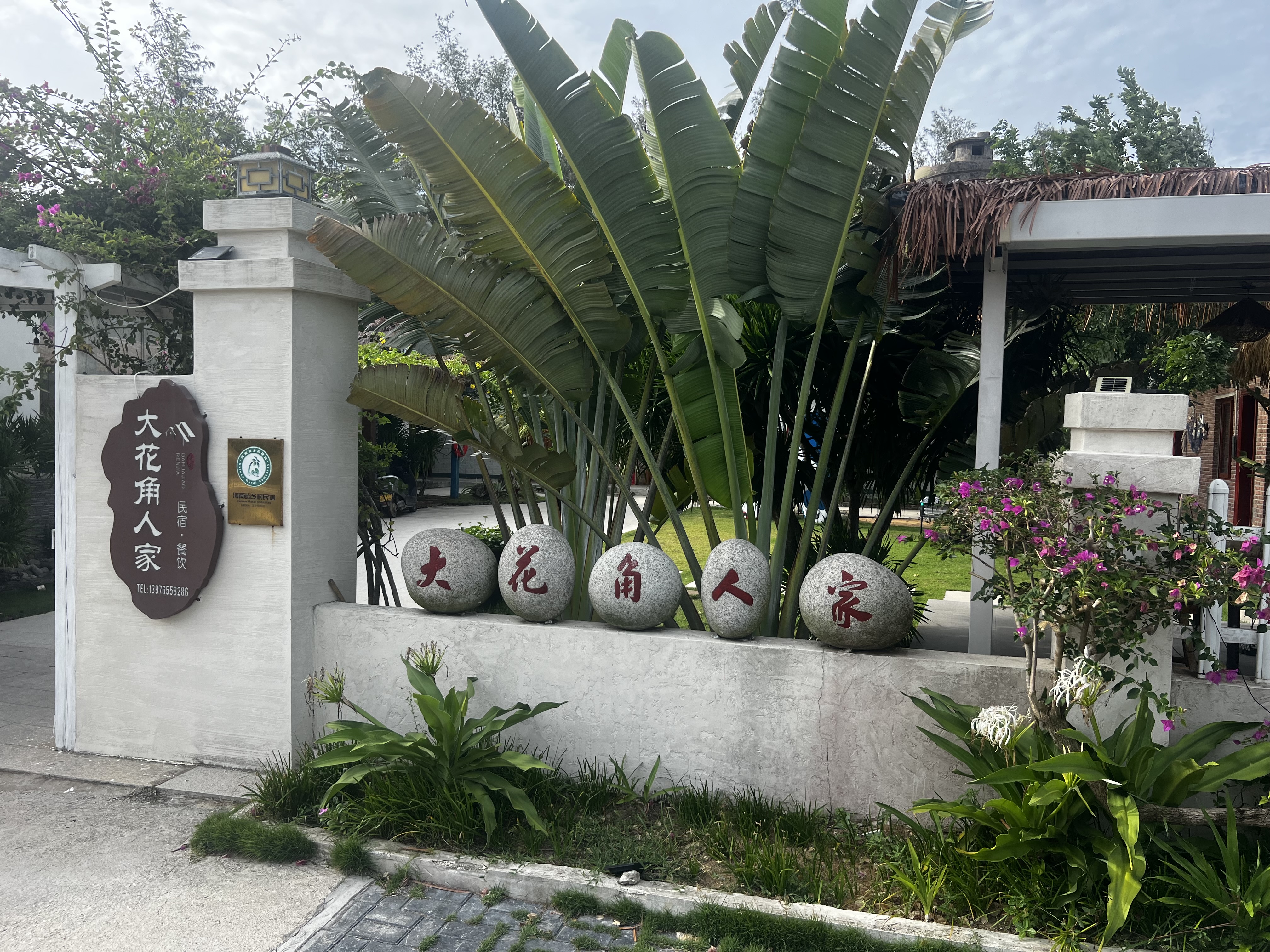 Dahuajiao Renjia entrance gate with stone name markers and tropical plants