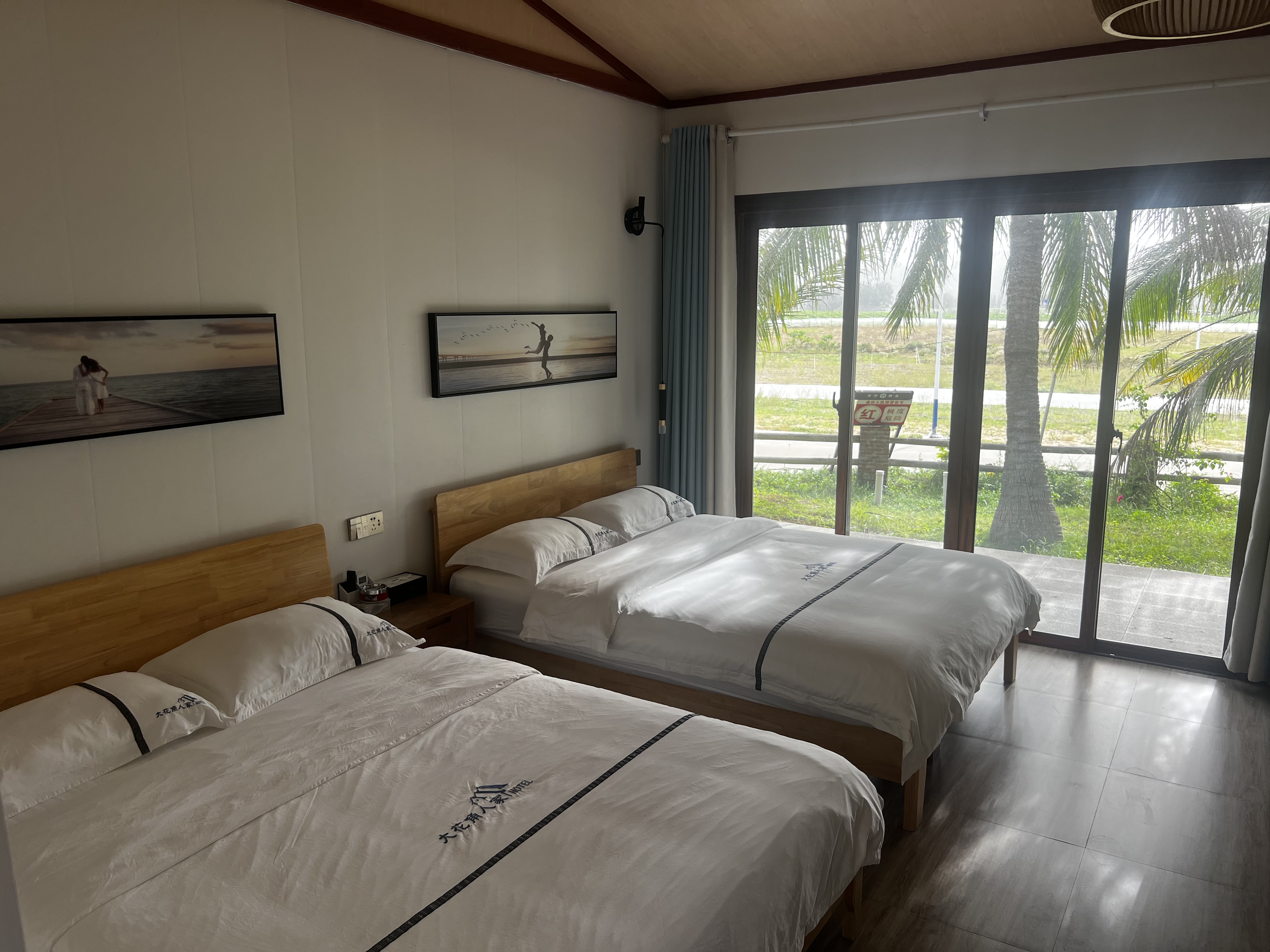 Spacious twin bedroom with white bedding and ocean view through glass doors