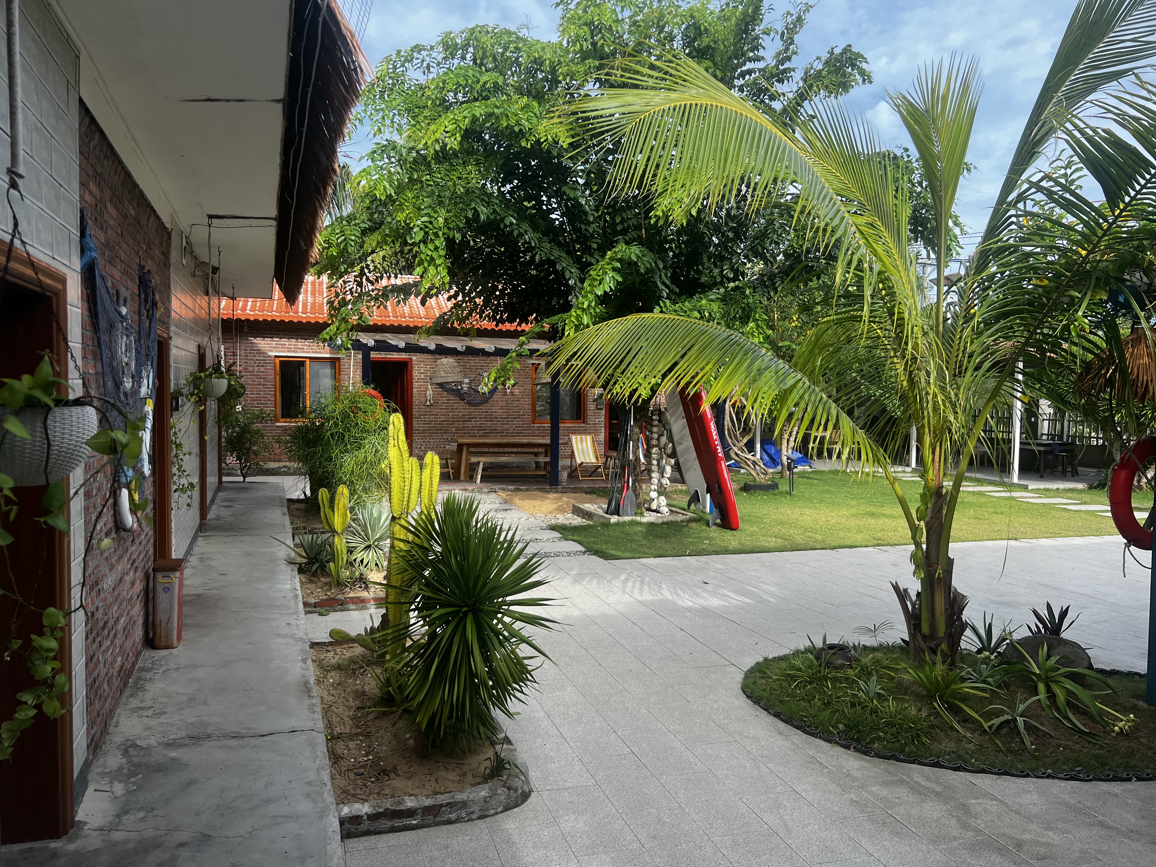 Landscaped garden courtyard with palm trees, cactus, and paddleboards